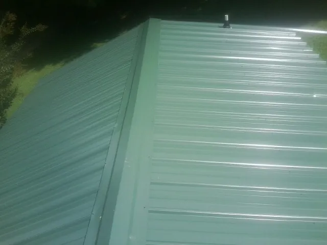 New green metal panels meeting at the ridge of a roof — Flat Roof Repair work by our crew in Jelm