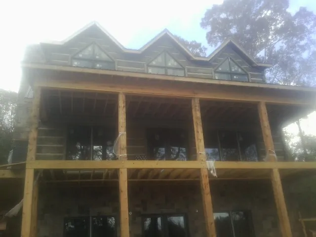 Dormers and porch framing on a large log home under construction — Roof Coating work by our crew in Jelm