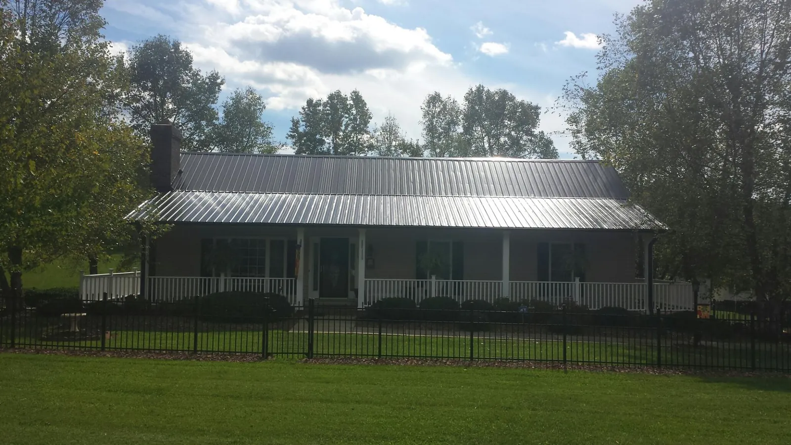 Gray metal roof on a brick ranch with a full width front porch — Gutter Guard Installation work by our crew in Jelm