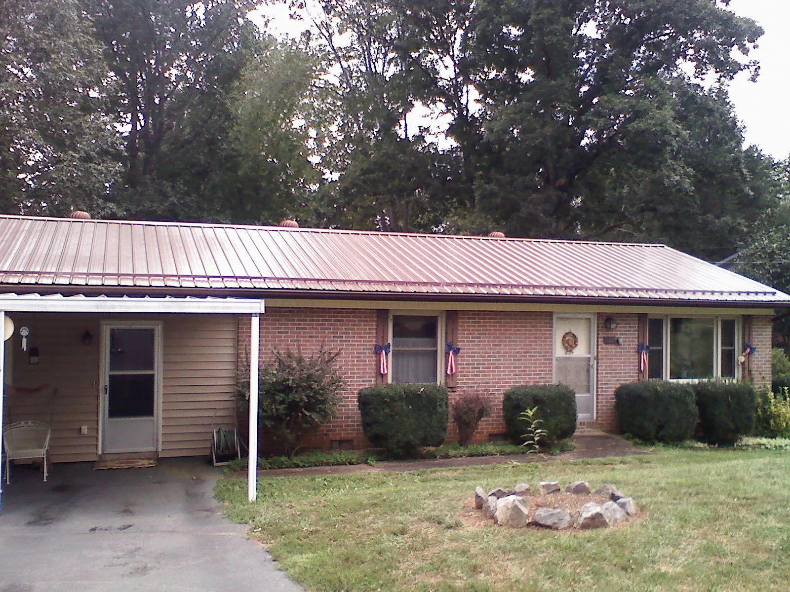 Bronze metal roof and carport on a brick ranch home — Roof Repair work by our crew in Jelm