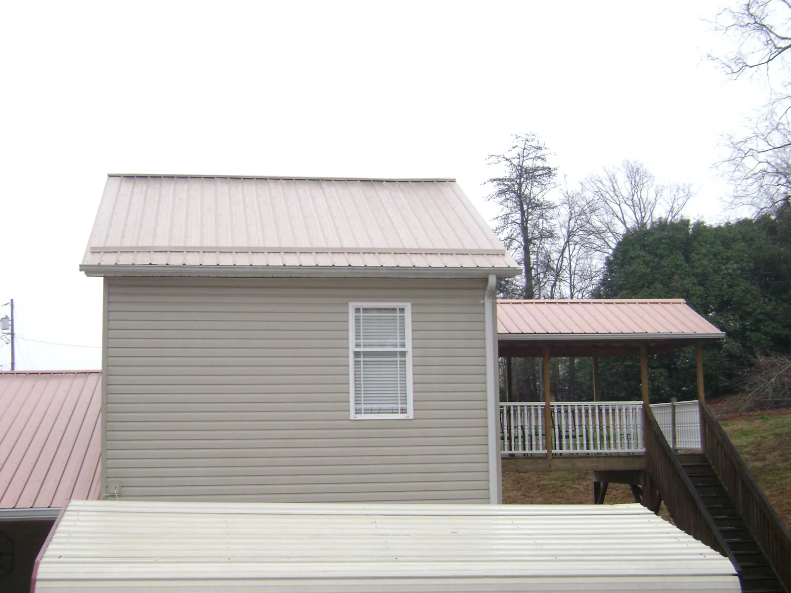 Tan metal roofs on a two story addition and attached porch, from a Roof Replacement job in Jelm