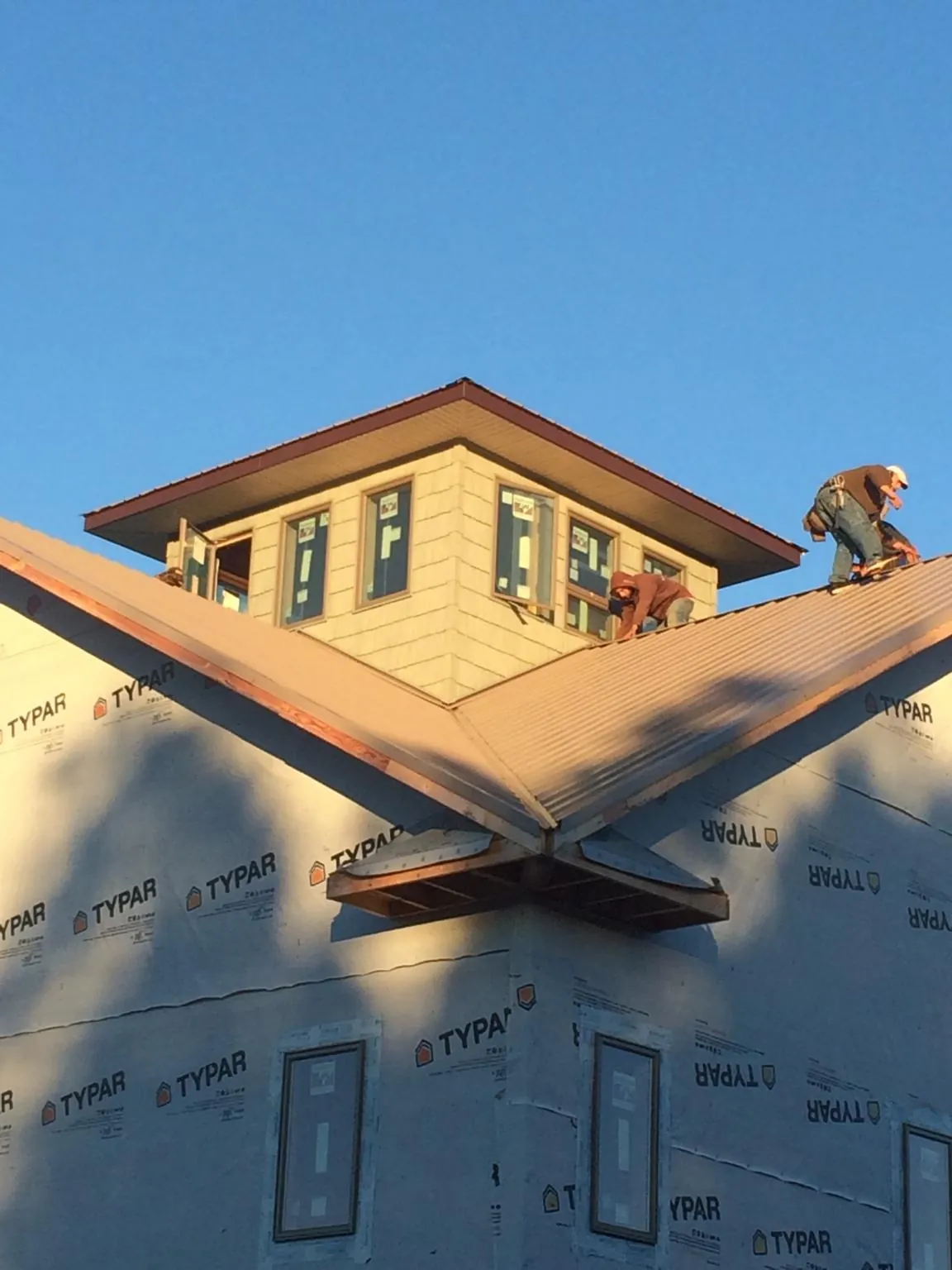 Roofers working around a rooftop cupola on a new metal roof at sunset — Roof Waterproofing in Jelm by Roofing Brothers